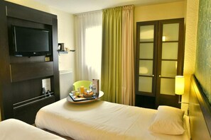A hotel room with two beds, a television, a tray with breakfast items, and a lamp. - Hotel Inn Design Chambery - La Ravoire (La Ravoire)
