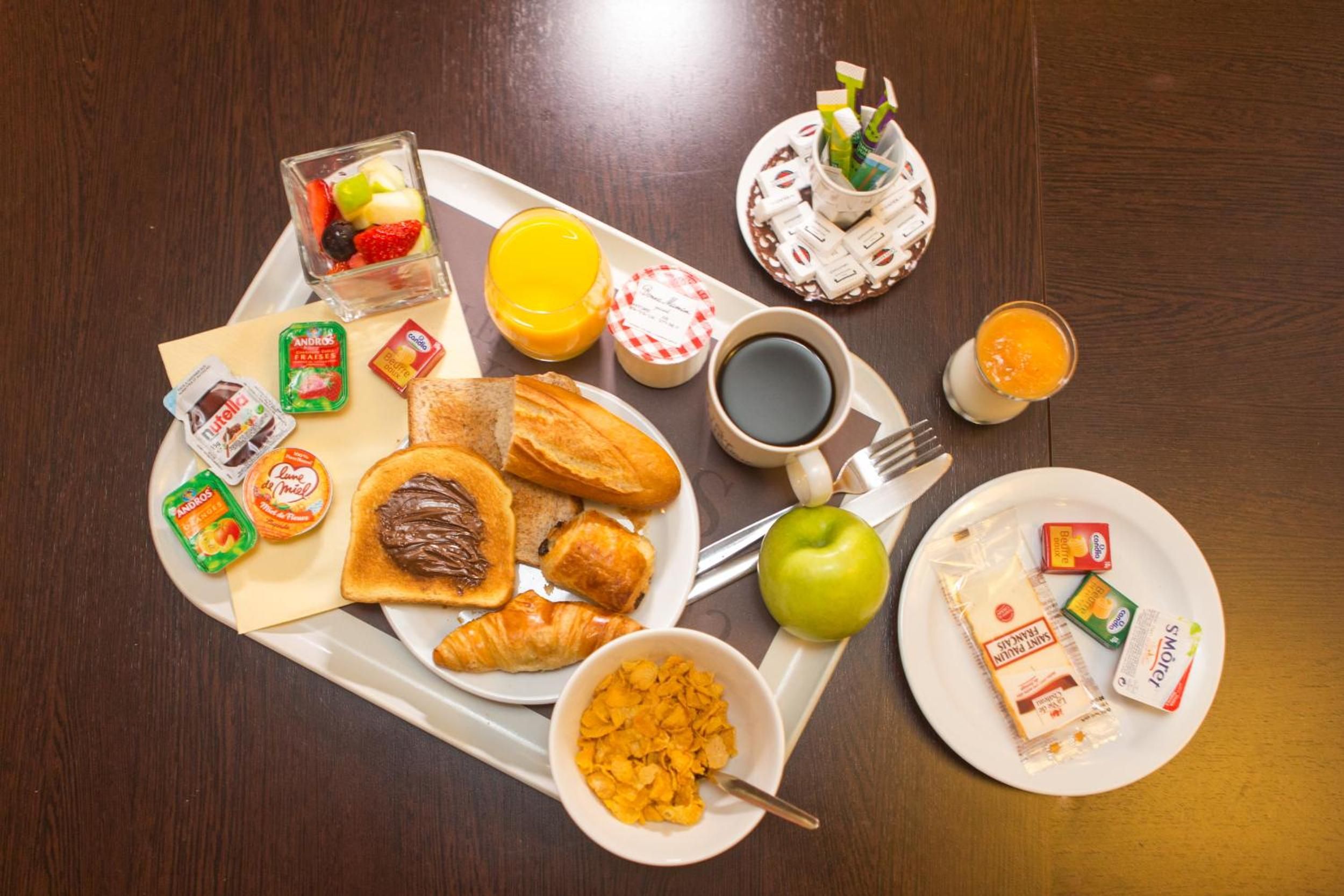 A breakfast tray with toast, croissants, cereal, fruit, juice, and coffee.