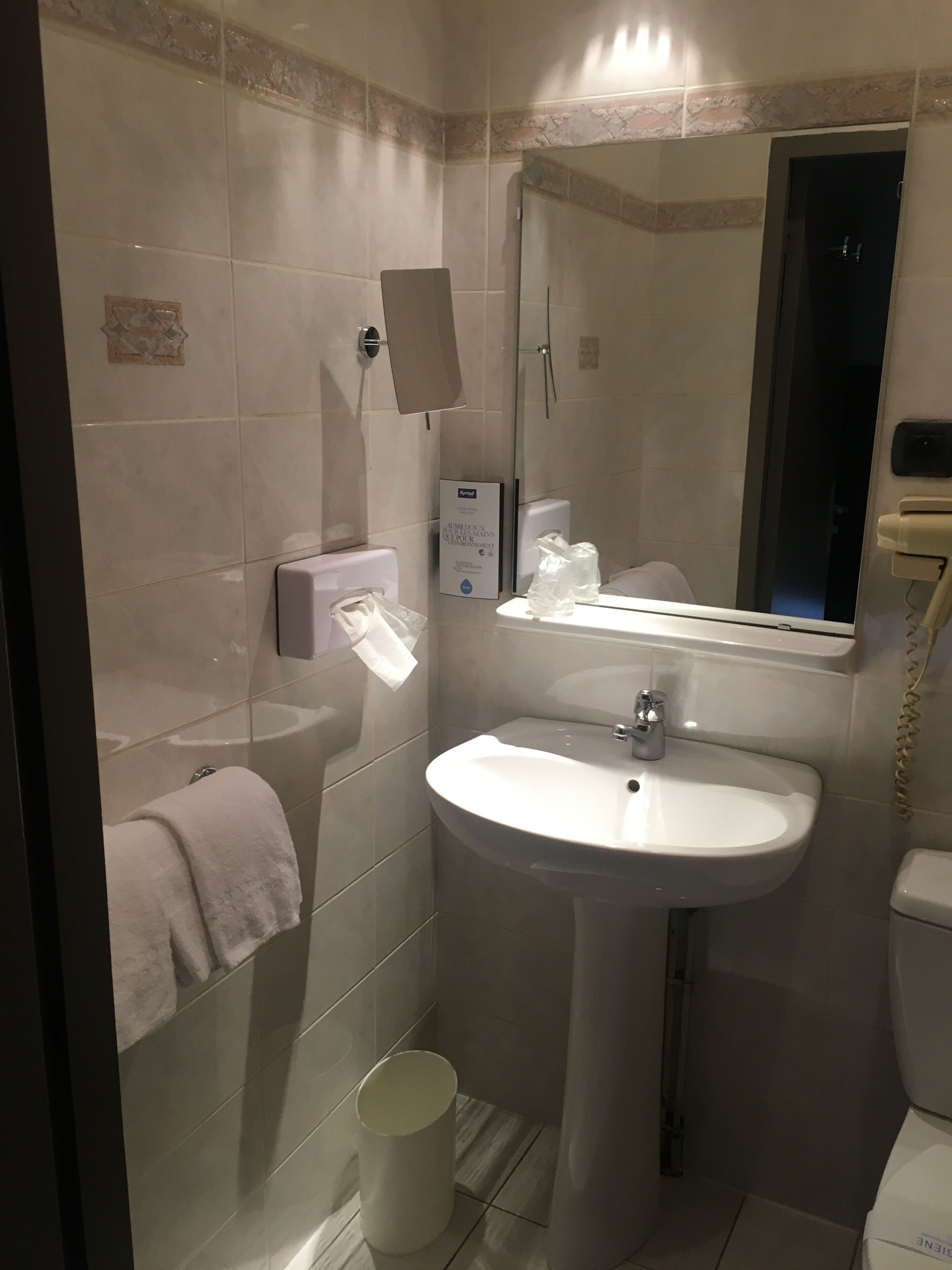 A bathroom with a white sink, a mirror, a towel rack, and a glass shower enclosure.