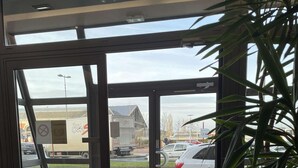 A hotel entrance with a glass door, a potted plant, and a view of the street outside. - Hotel Kyriad Rodez (Rodez)