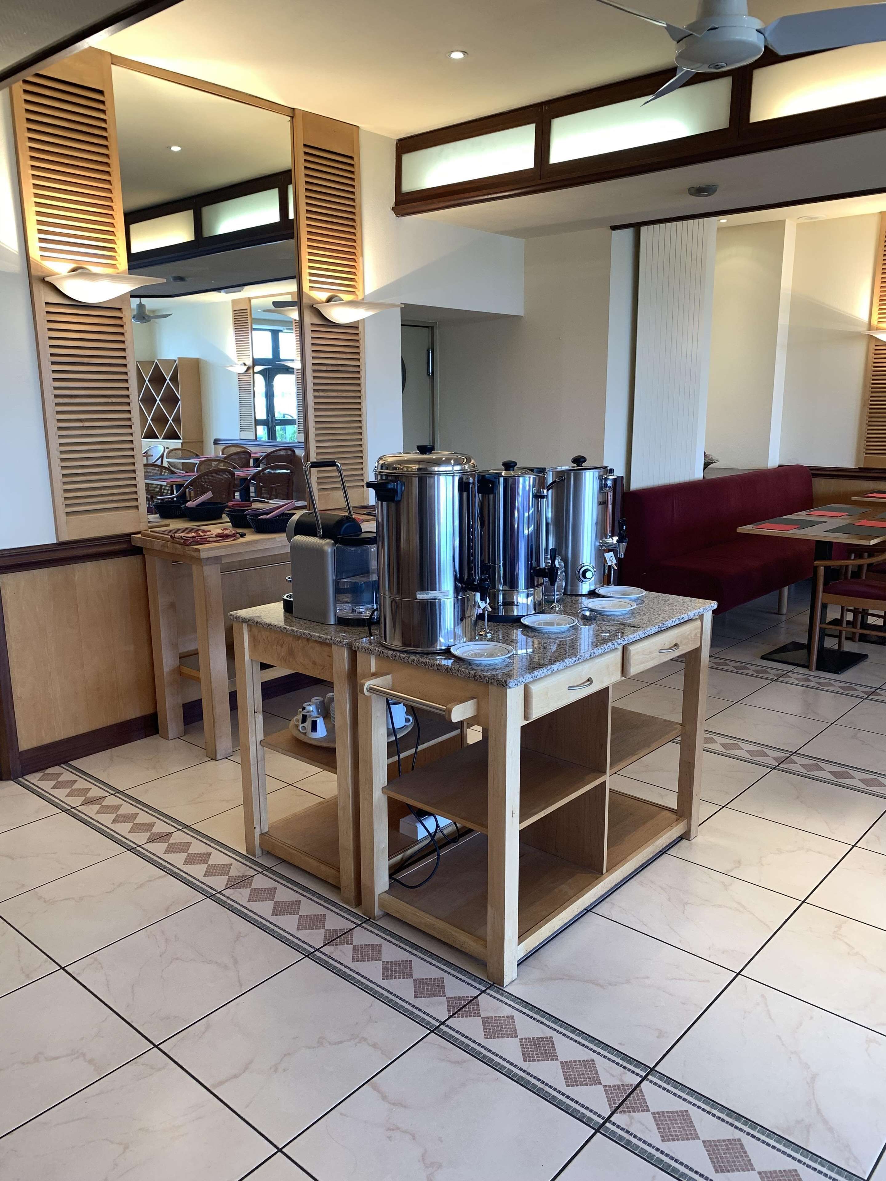 A kitchen area with stainless steel appliances, a wooden table, and a red couch.