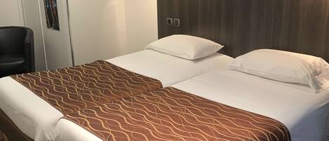 A double bed with a brown patterned bedspread, a wooden headboard, and a small bedside table.