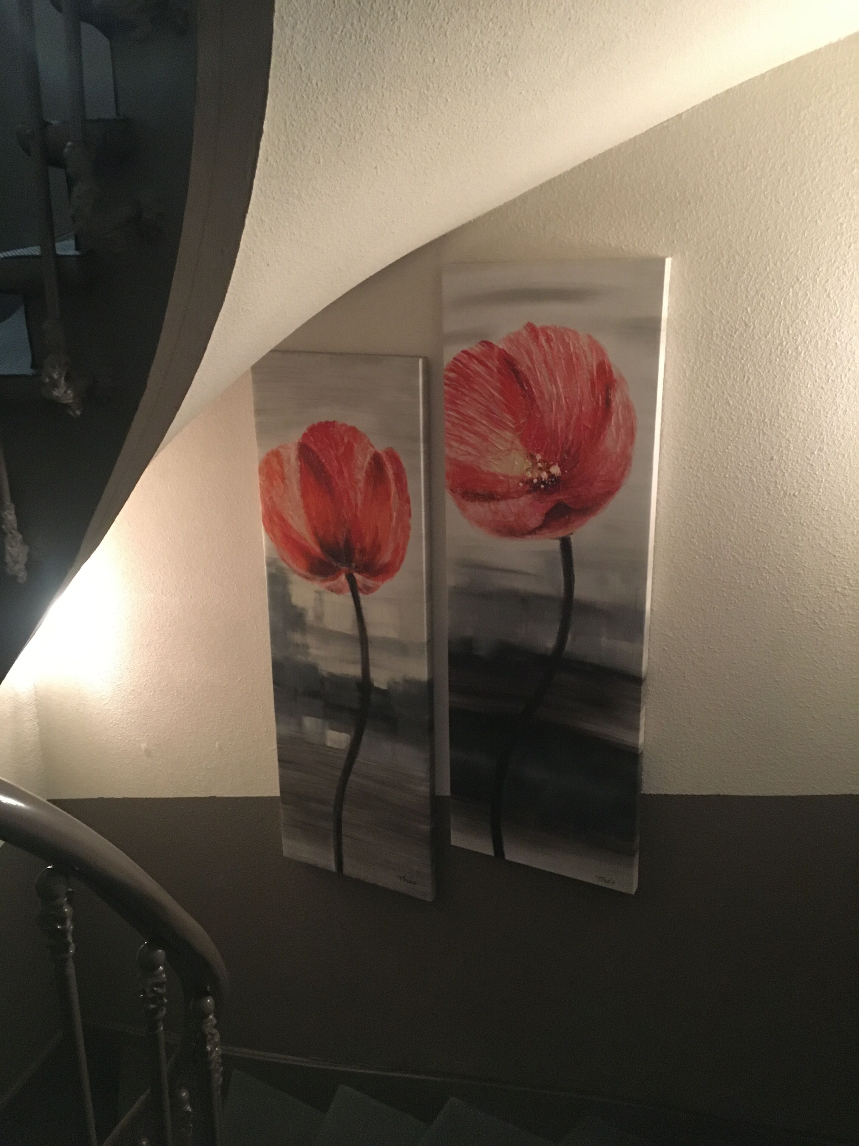 Duas pinturas de flores vermelhas em uma parede.