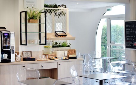 A modern cafe with clear glass chairs, a coffee machine, and a menu board.