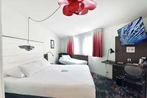 Et hotelværelse med en stor seng, et skrivebord, en stol, et fjernsyn og et vindue med gardiner.