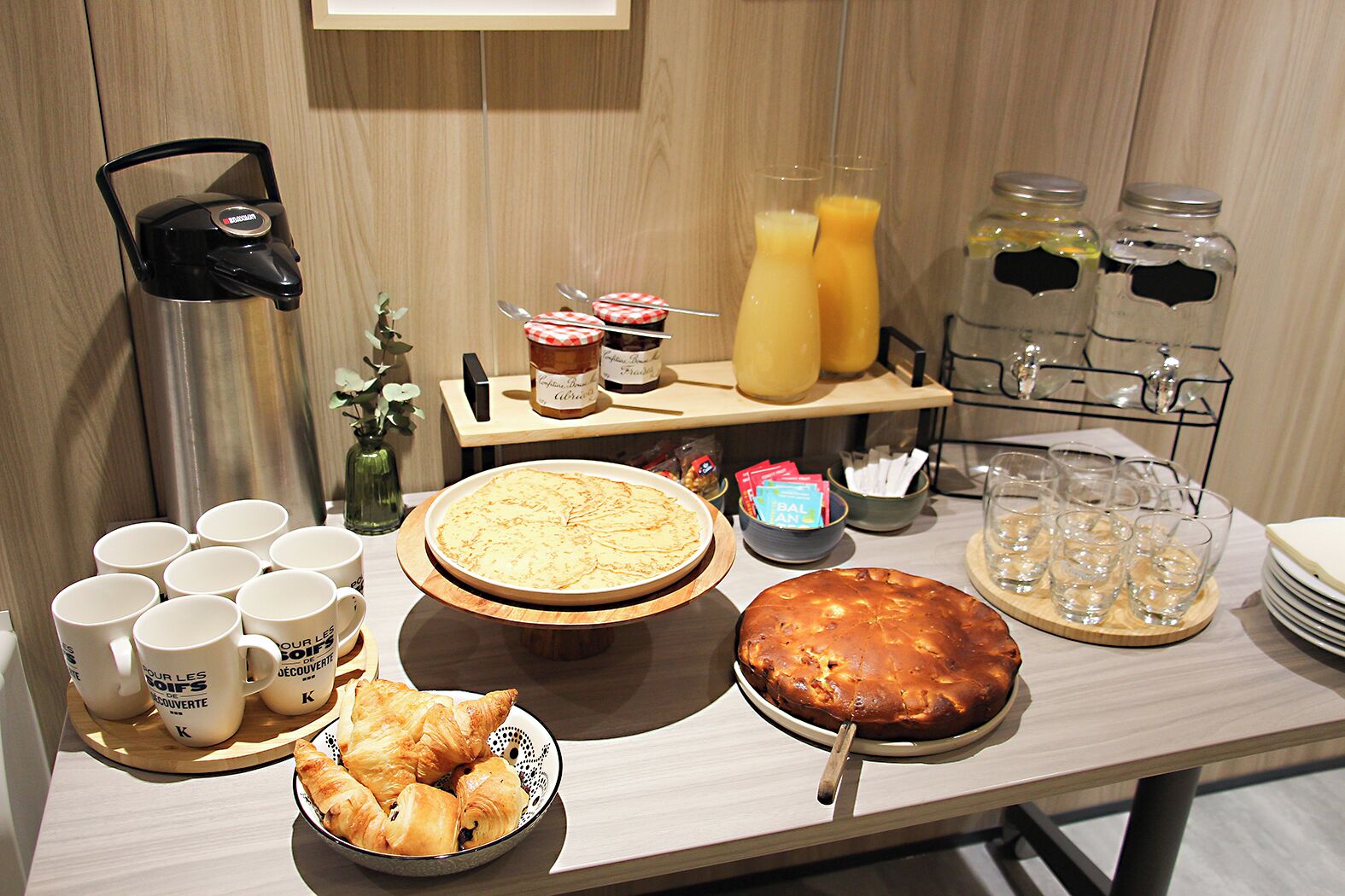 A breakfast buffet with various food items, including pastries, a pie, and juice.
