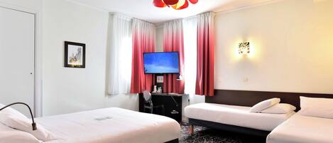 A hotel room with two beds, a desk with a computer, a TV, and a red pendant light.