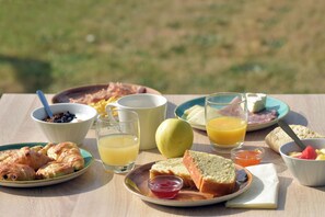 Et morgenbord med croissanter, brød, frugt og drikkevarer.