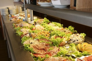 Buffet com diversos alimentos, incluindo saladas, carnes e frutas.