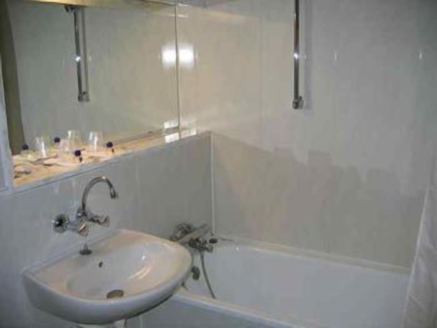 A bathroom with a sink, mirror, and bathtub.