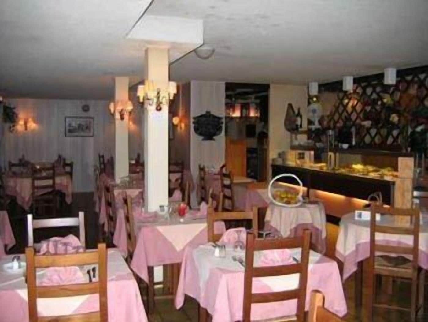 A restaurant with pink tablecloths and wooden chairs, featuring a buffet area with a variety of dishes.