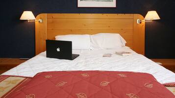 Un lit bien fait, avec un ordinateur portable, des oreillers et une couverture rouge.