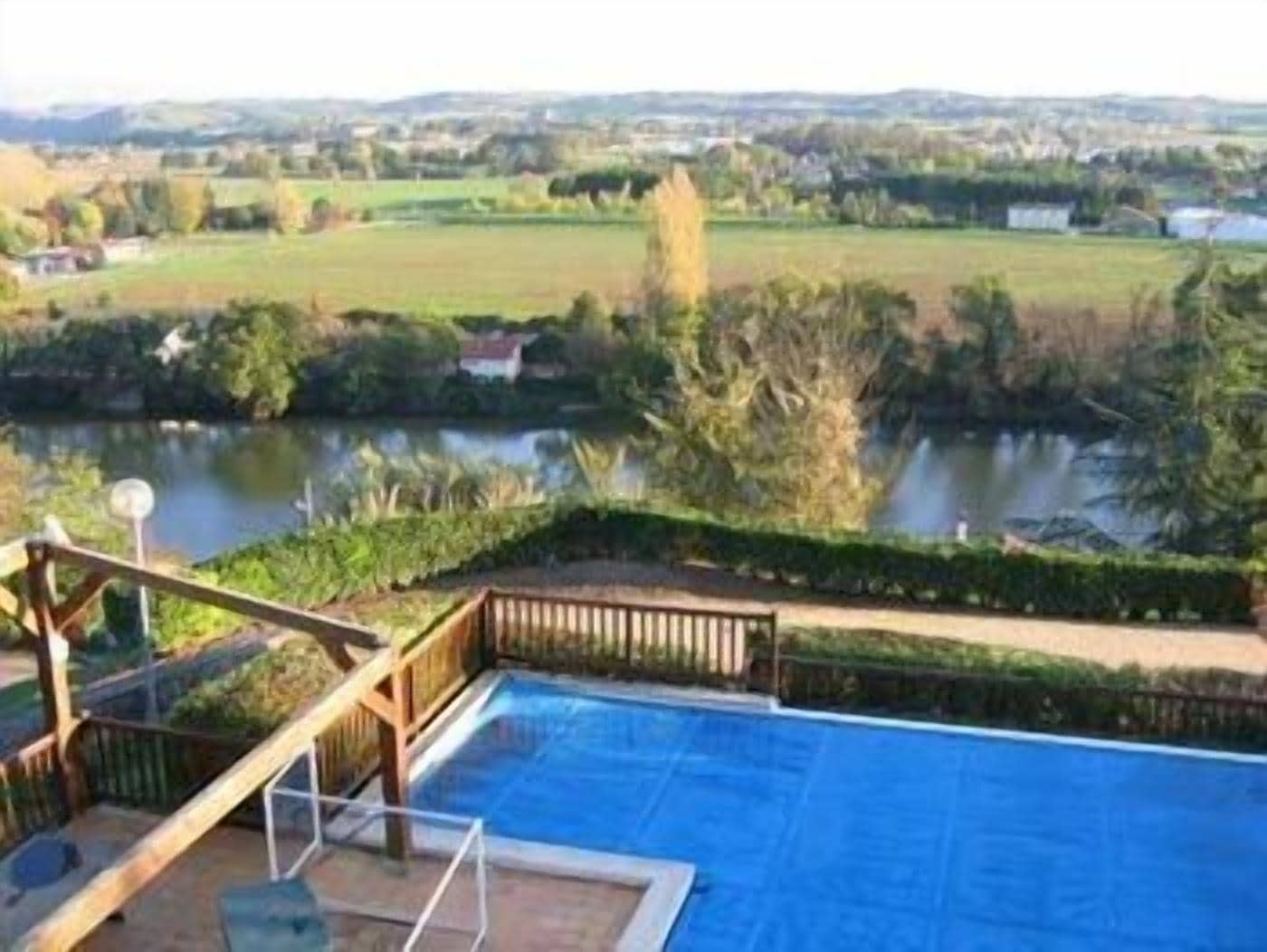 A swimming pool with a wooden deck and a view of a lake and surrounding landscape.