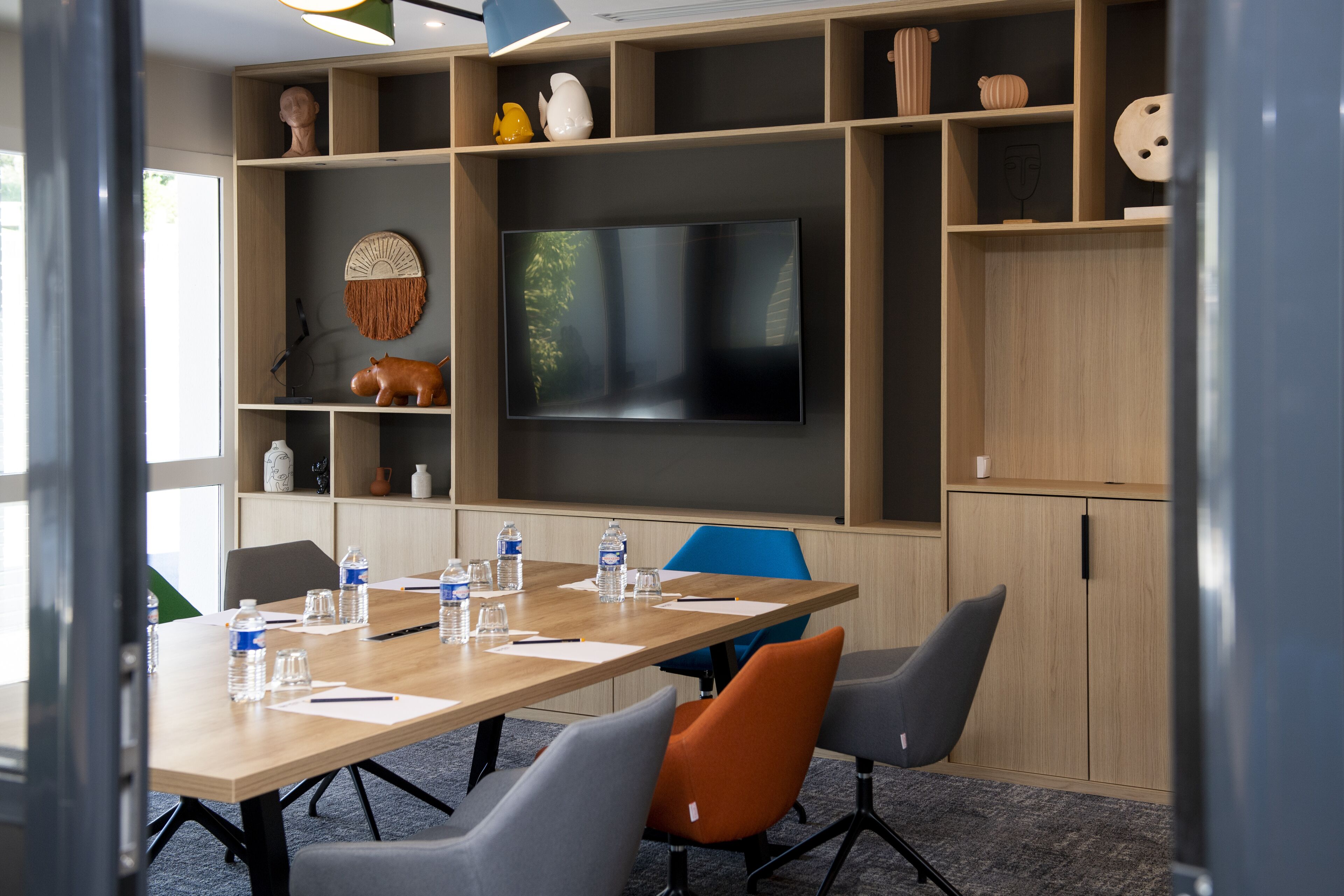 A conference room with a large flat-screen TV, wooden tables, and chairs.