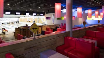 A bowling alley with red seating and a caution sign for slippery floors.