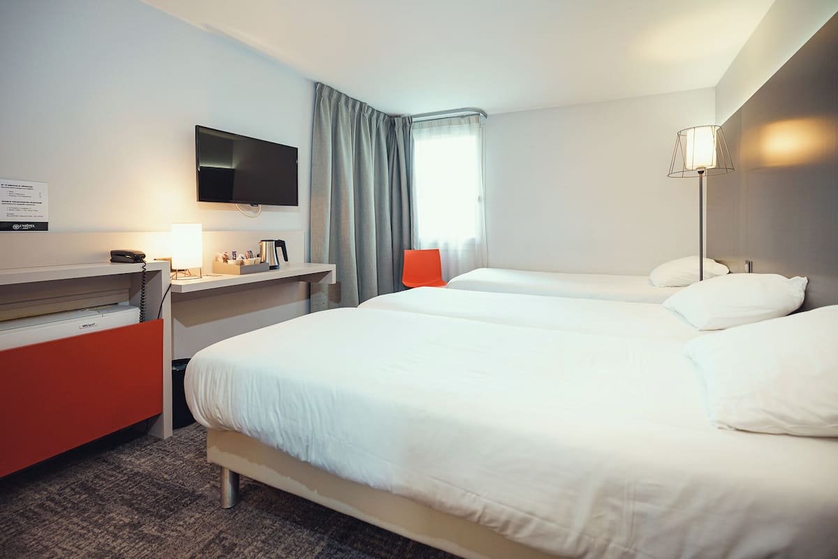 Una habitación de hotel con una cama, un escritorio con teléfono, un televisor y una lámpara.
