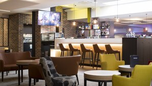 A modern bar area with seating and a television screen.