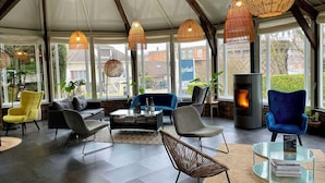 A modern lounge area with wicker pendant lights, comfortable seating, a glass coffee table, and a fireplace. - Kyriad Epernay (Epernay)