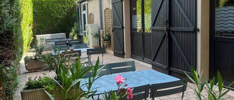 A patio area with outdoor seating, planters, and a building with large windows and a gated entrance.