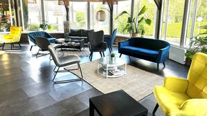 A spacious indoor area with a modern design, featuring a large sofa, armchairs, and a coffee table. - Kyriad Epernay (Epernay)