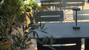An outdoor patio area with tables and chairs, surrounded by greenery and a hedge. - Kyriad Epernay (Epernay)