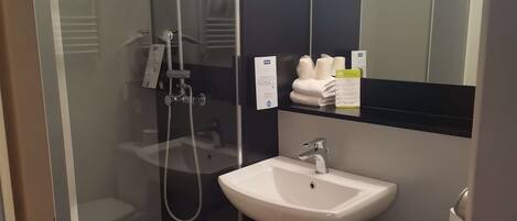 A modern bathroom with a glass-enclosed shower, a white sink, and a toilet.