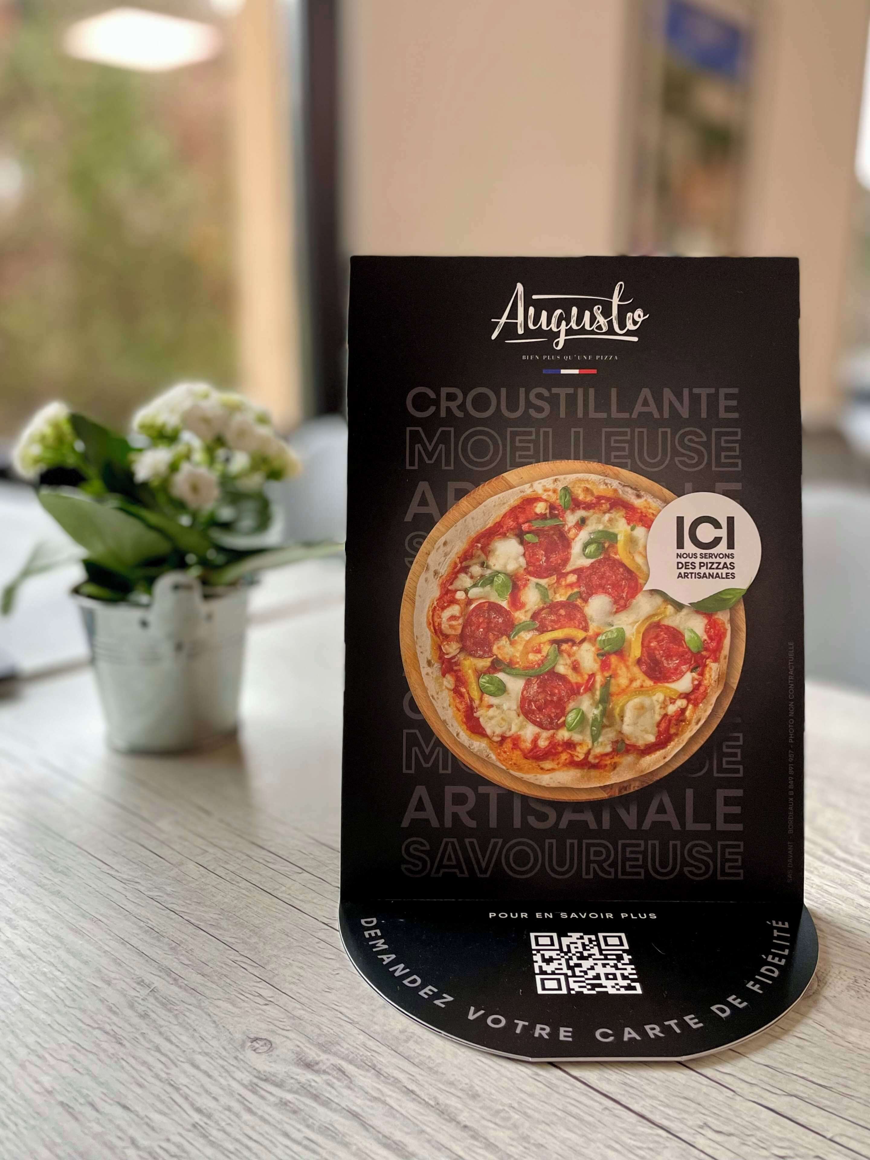 Un letrero negro con un código QR y texto en francés, sobre una superficie de madera.
