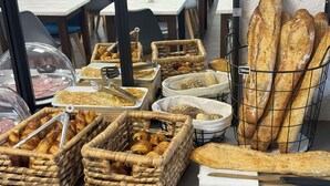 A bakery display with various breads and pastries in baskets and a wire rack. - Kyriad Epernay (Epernay)