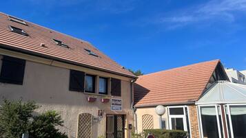A hotel with a tiled roof, a sign indicating 'Kyriad Hotel', and a no parking sign.
