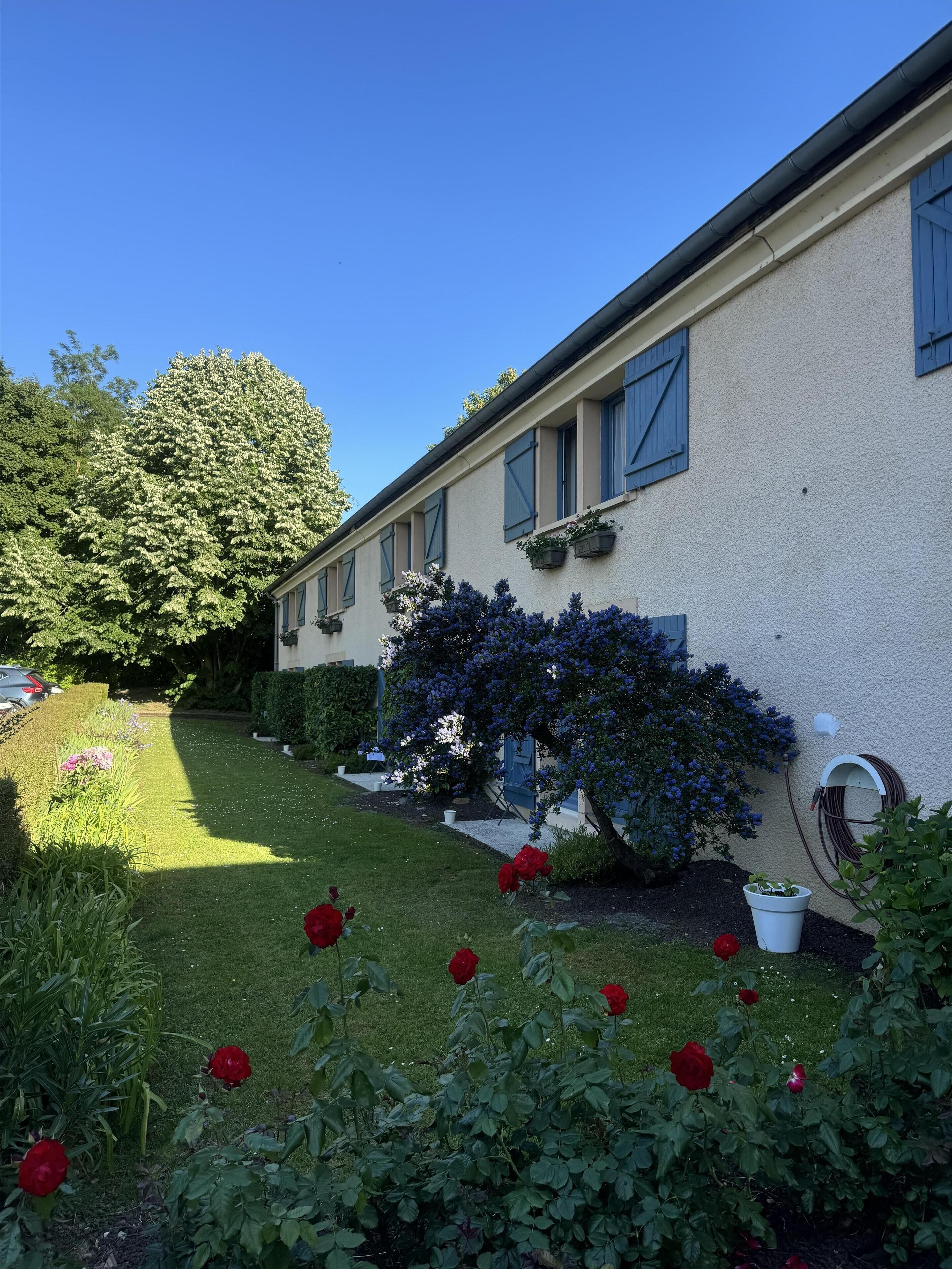A building with a garden, including roses and a tree.