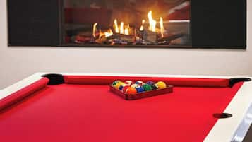 Una mesa de billar con superficie de fieltro rojo y un juego de bolas de colores en el centro.