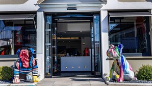 A building entrance with a glass door, a reception desk inside, and two colorful sculptures outside.