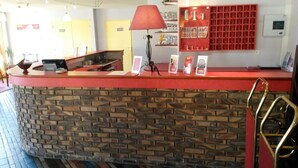 A reception area with a red counter, a brick wall, a red lamp, and a display of awards.