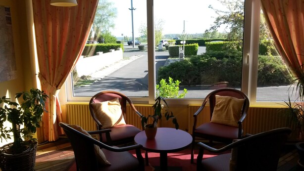 A room with two chairs and a small table, a window with curtains, and a potted plant.