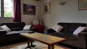 Un salon avec deux canapés, une table basse et des œuvres d’art accrochées aux murs.