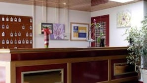 Un mostrador de recepción con un tablón de anuncios, obras de arte enmarcadas y una planta en maceta.