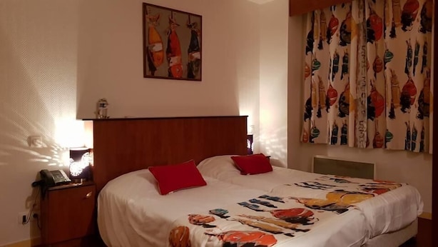 Une chambre d’hôtel avec un lit, une table de chevet, un téléphone et un tableau au mur.