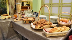 Un bufé de desayuno con pan, bollería y una estación de café.