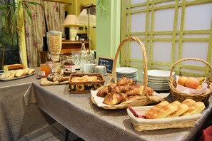 Buffet de café da manhã com pães, doces e uma estação de café.