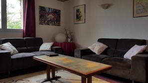 Uma sala de estar com dois sofás, uma mesa de centro e obras de arte nas paredes.