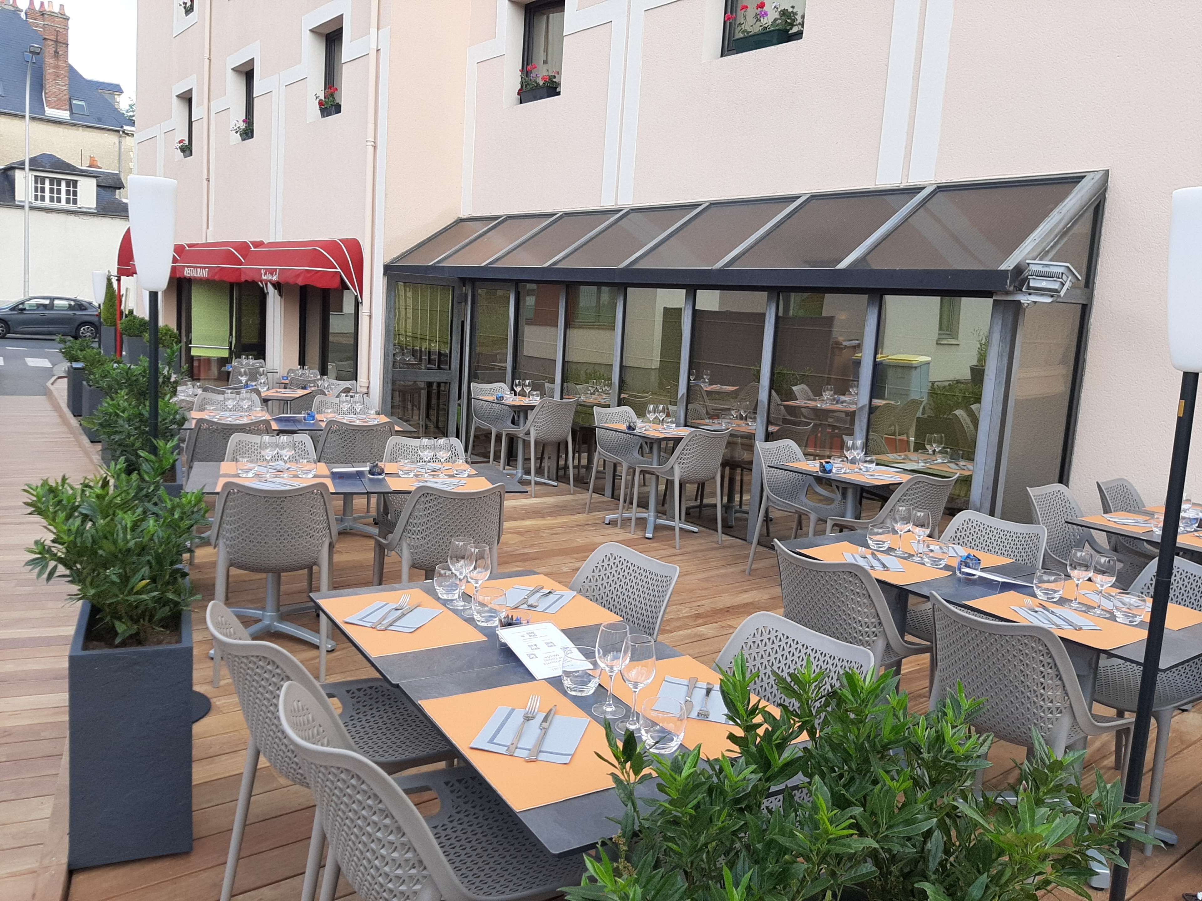 An outdoor dining area with tables and chairs, a covered section, and potted plants.