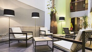 A modern lobby with seating areas, floor lamps, and a large decorative plant.