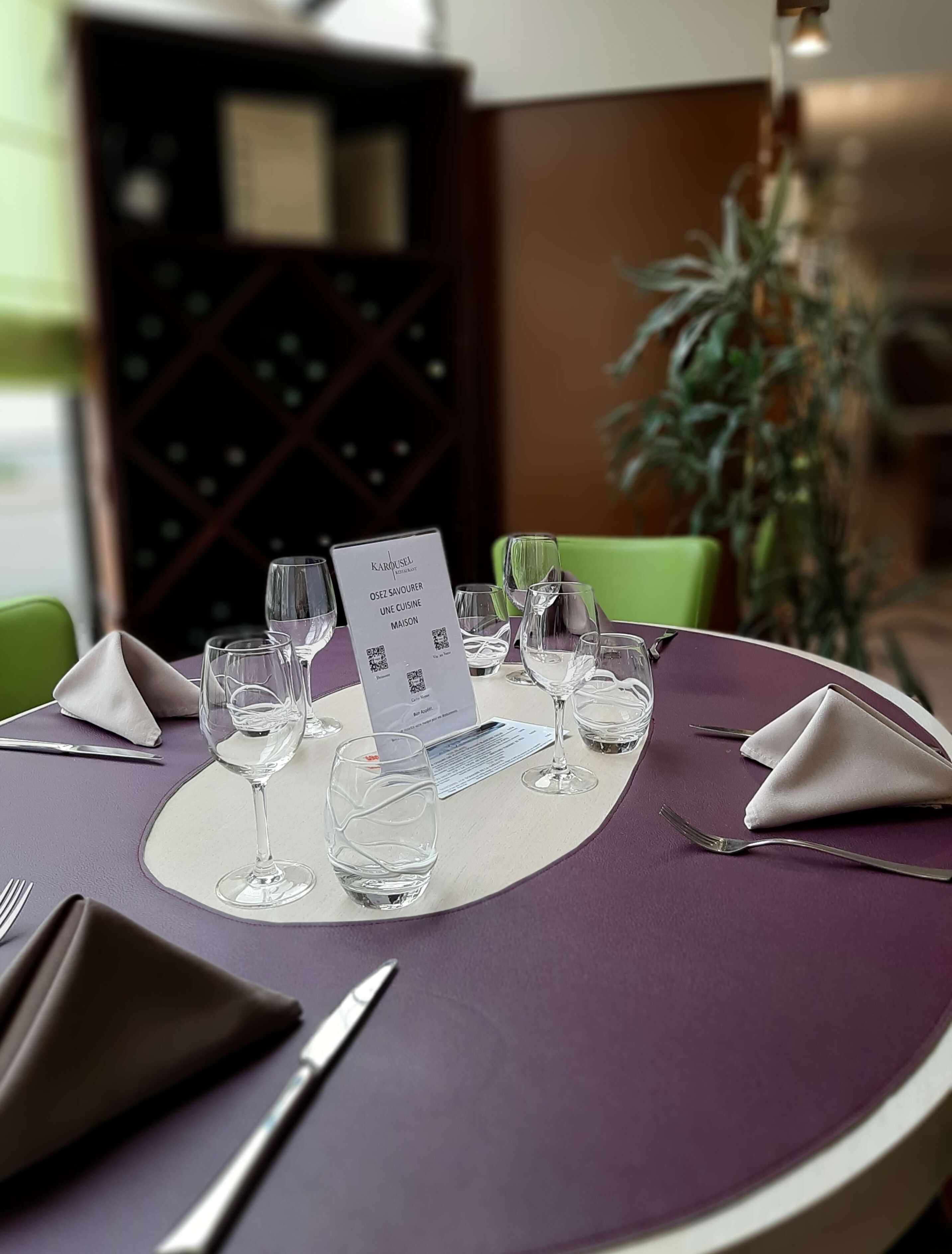 A dining table set with wine glasses, a menu, and folded napkins.