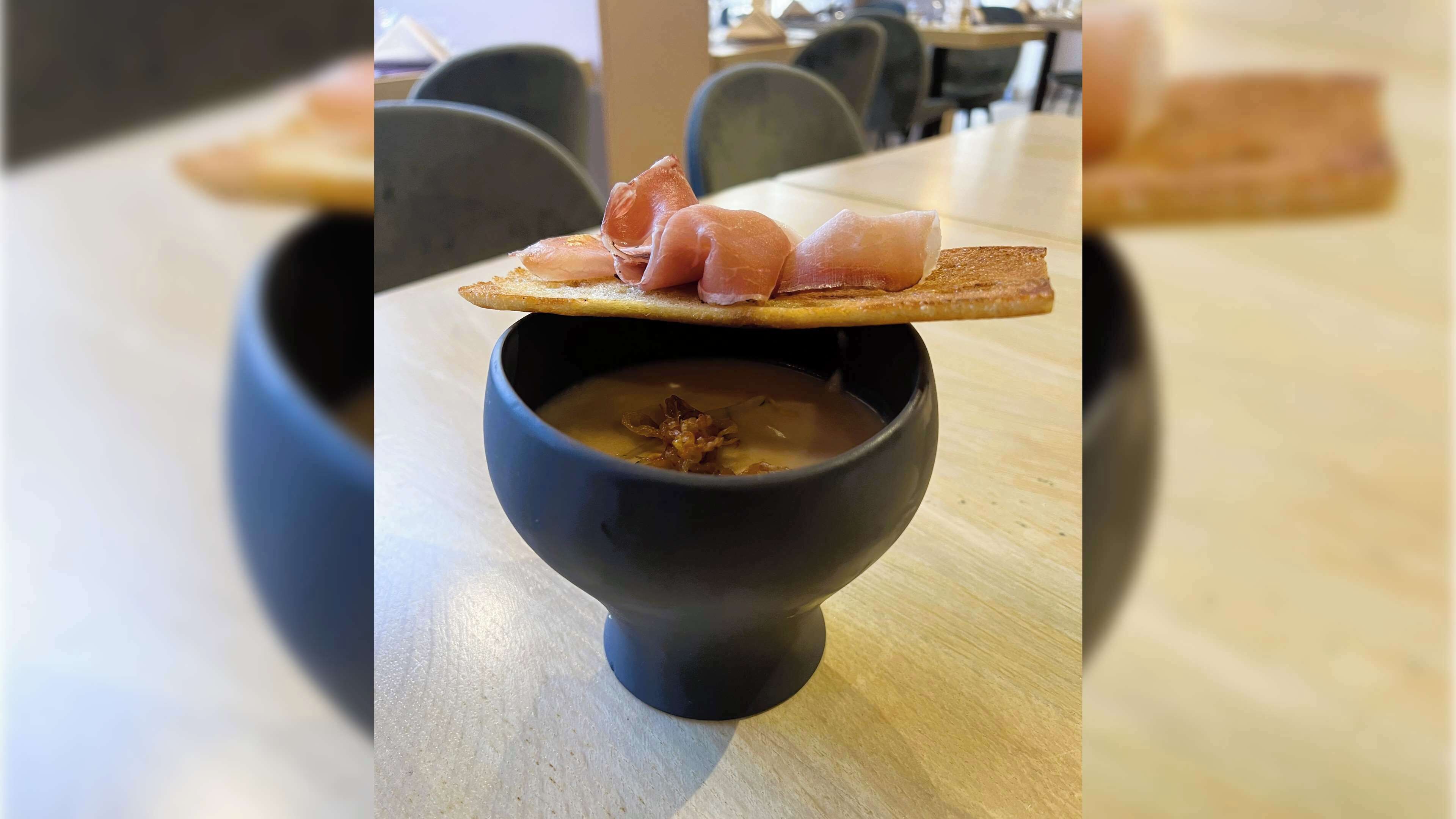 A bowl of soup with a piece of bread on top.