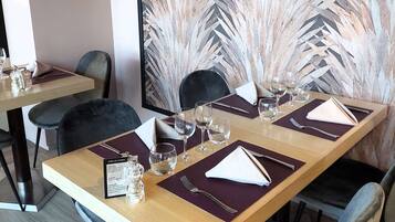 A restaurant with a long wooden table set for four, including wine glasses and cutlery.