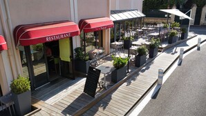A restaurant with outdoor seating, red awnings, and a wooden deck.