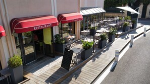 A restaurant with outdoor seating, red awnings, and a wooden deck.