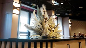 Una zona de recepció amb un disseny de sostre modern, un arranjament decoratiu de plantes i un mostrador amb acabat de fusta.