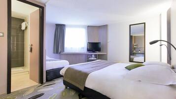 Quarto de hotel com duas camas, banheiro, televisão e espelho.
