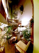 Un amplio salón con escaleras, un árbol de Navidad y varios conjuntos de asientos.